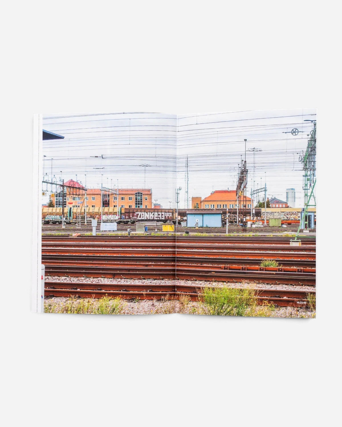 Open pages of Astrofat 136 Minutes of Malmö zine showing a freight train yard with graffiti-covered rail cars