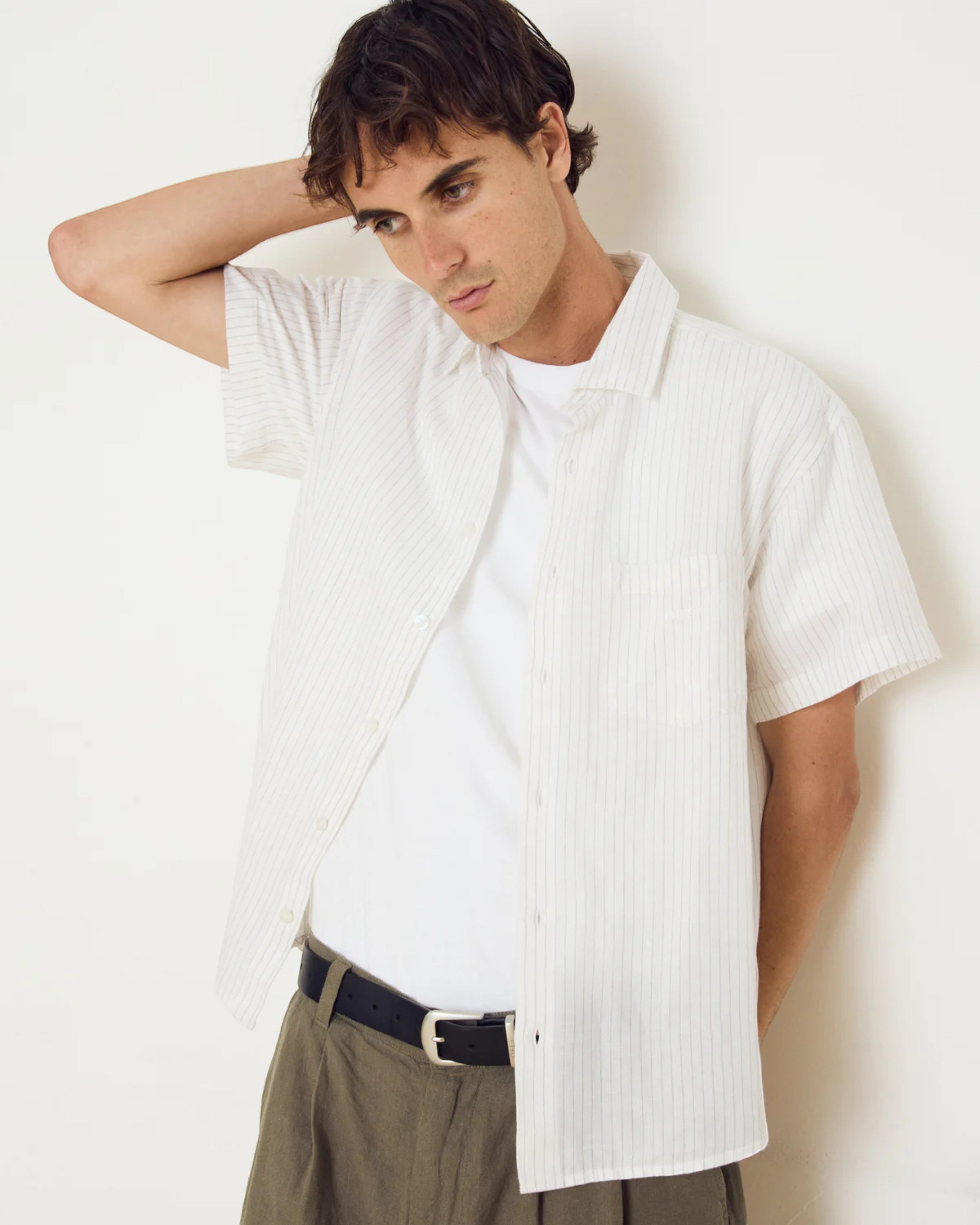 Astrofat Barry Woven short-sleeve button-up shirt in off-white with thin vertical pinstripes, worn open over a white t-shirt.