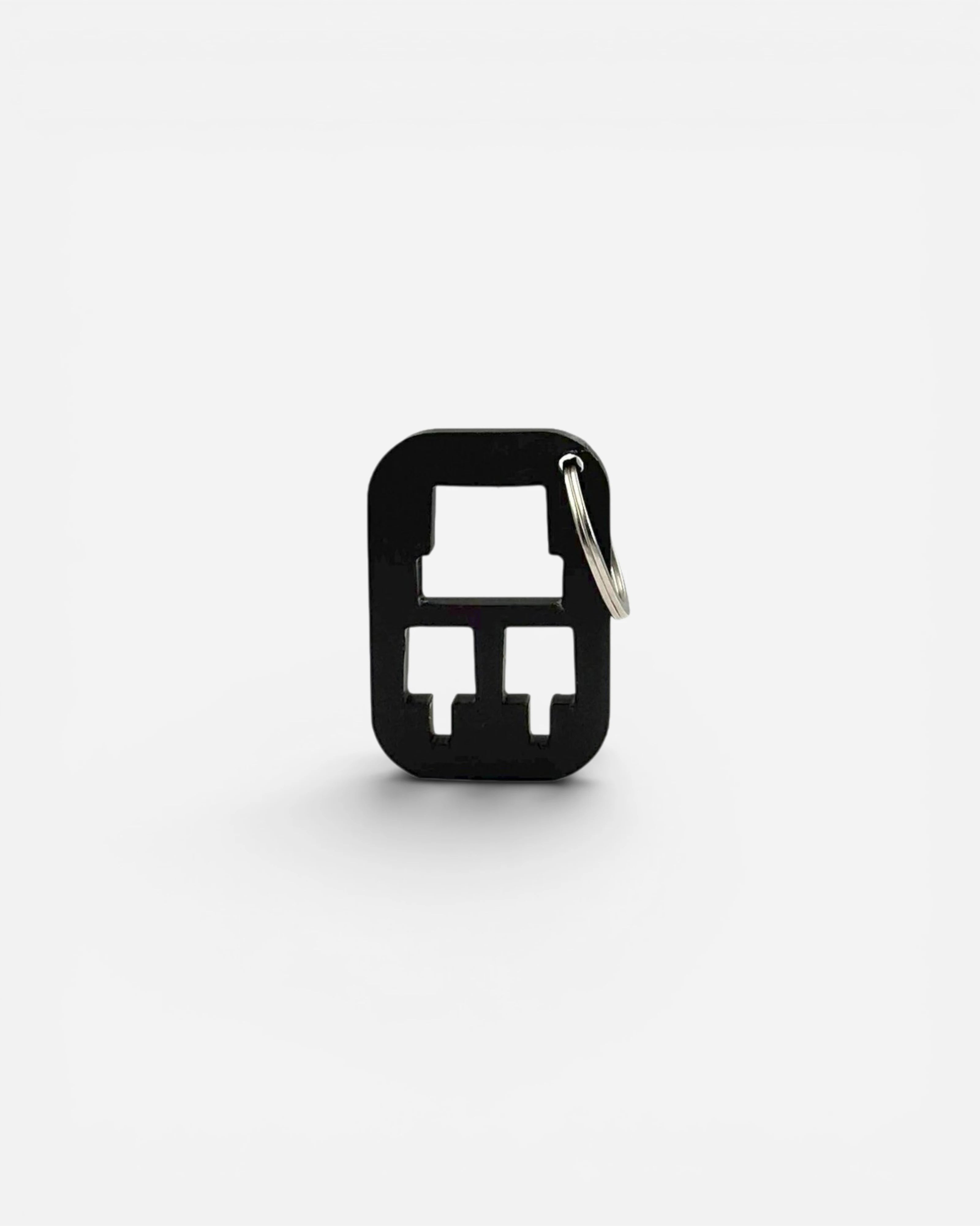 black metal keychain designed to hold replacement caps, with cutouts for two caps and a keyring.