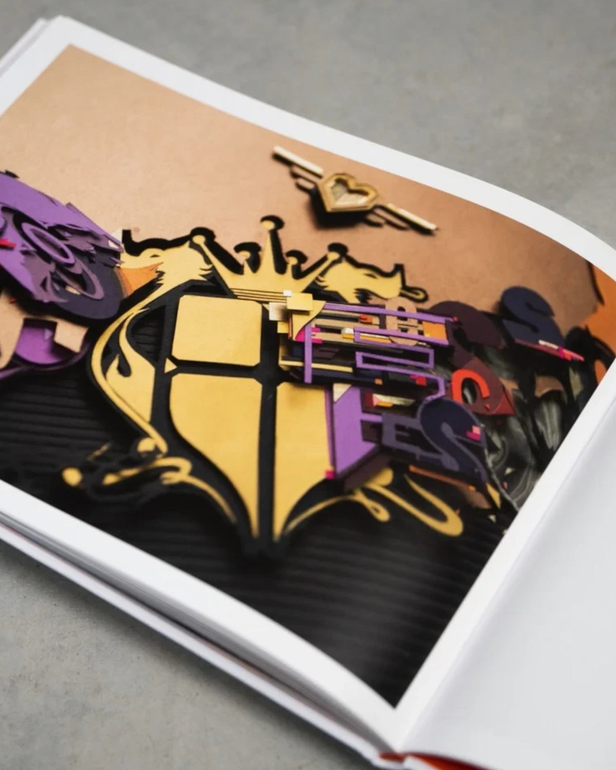 Astrofat DOES First 20 Years book open to a page showing layered graffiti art sketches and shield designs.