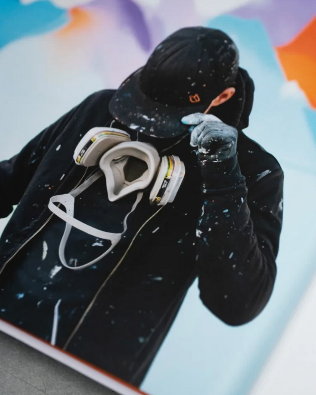 Astrofat DOES First 20 Years book page showing a photo of the artist wearing a respirator and paint-splattered hoodie