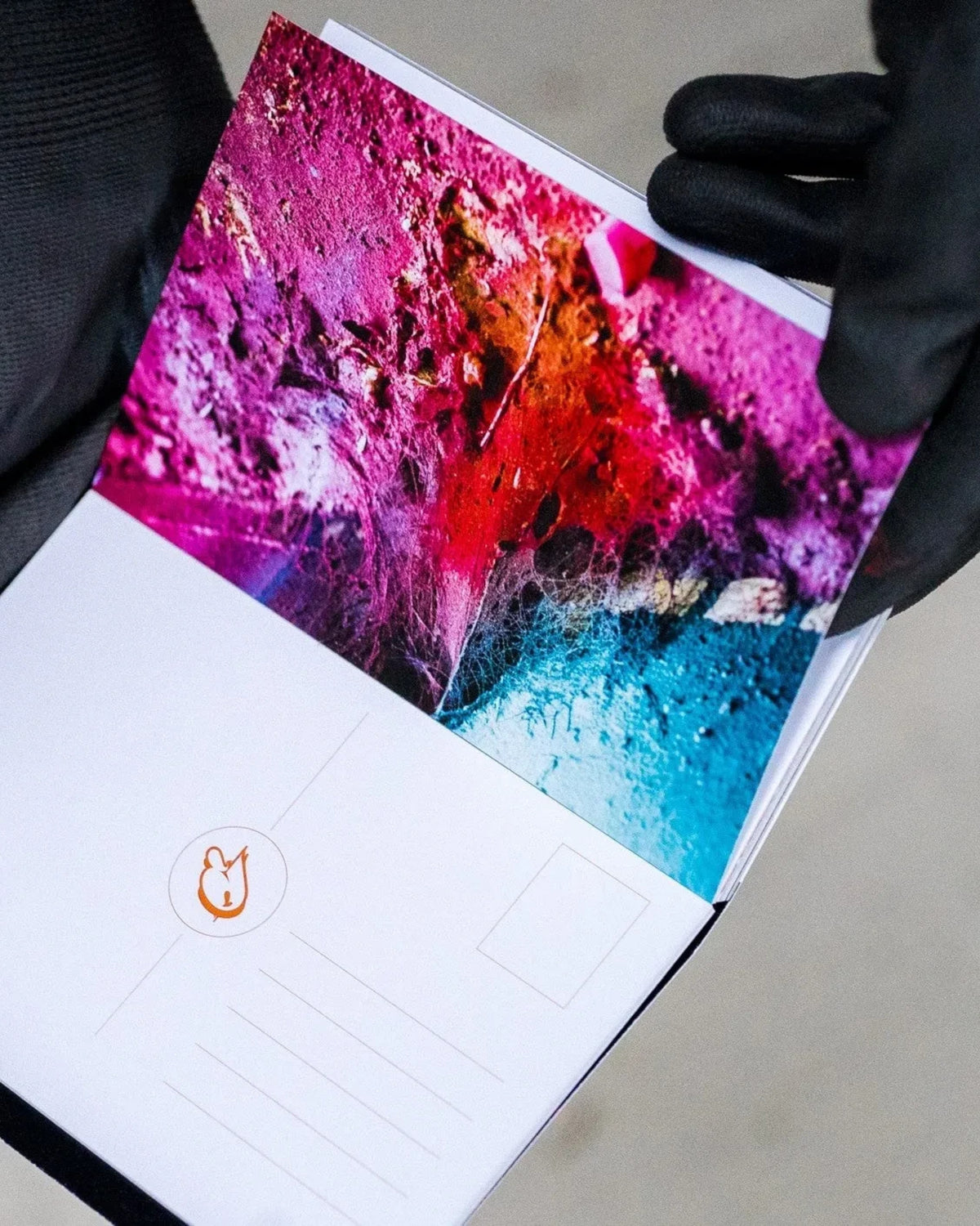 Astrofat DOES Fragments postcard set N°1 featuring a vibrant abstract art print on white cardstock held by gloved hands.