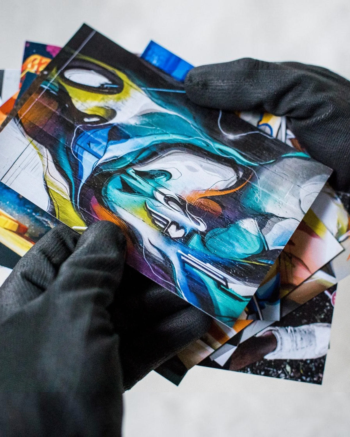 Astrofat DOES Fragments postcard set featuring vibrant abstract graffiti art designs held by gloved hands.
