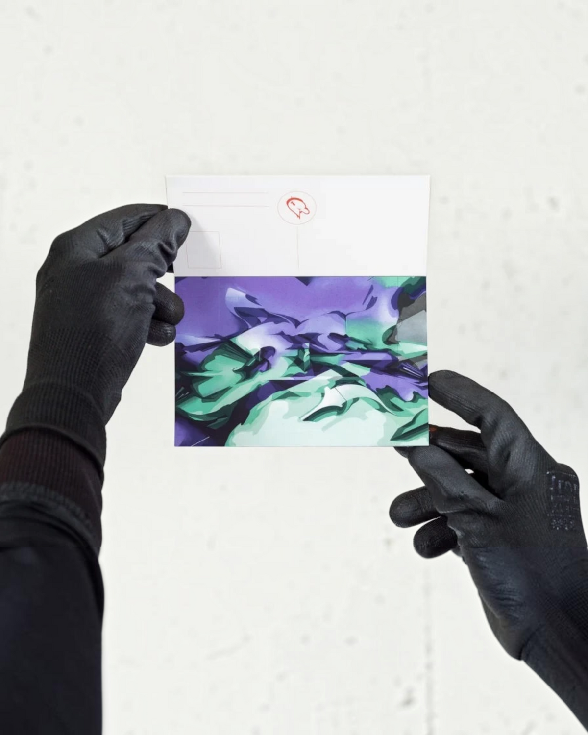 Astrofat DOES Close Up postcard featuring abstract purple and green graffiti art held by hands in black gloves.