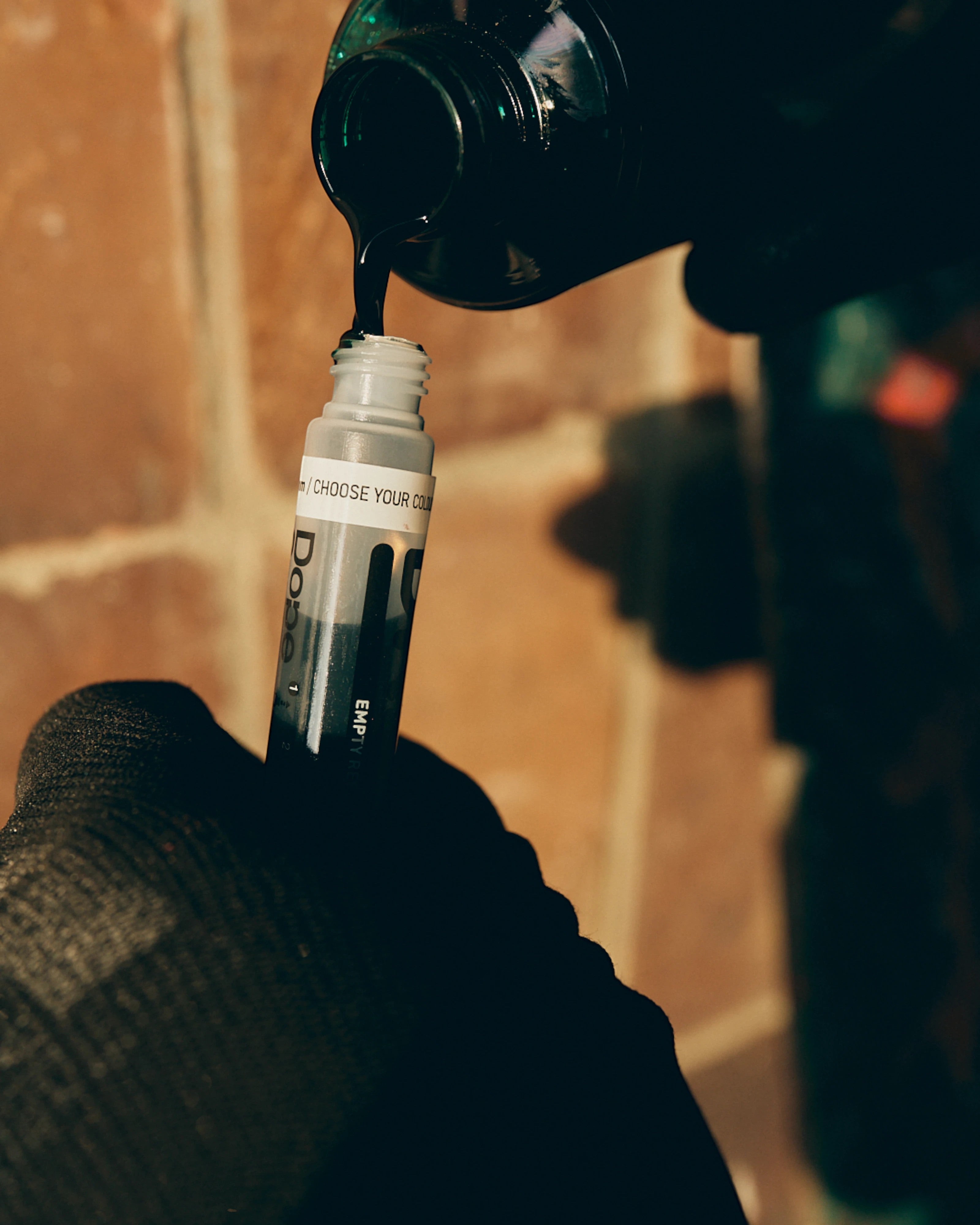 Astrofat Dope Liquid permanent black ink being poured into a refillable marker bottle for graffiti art
