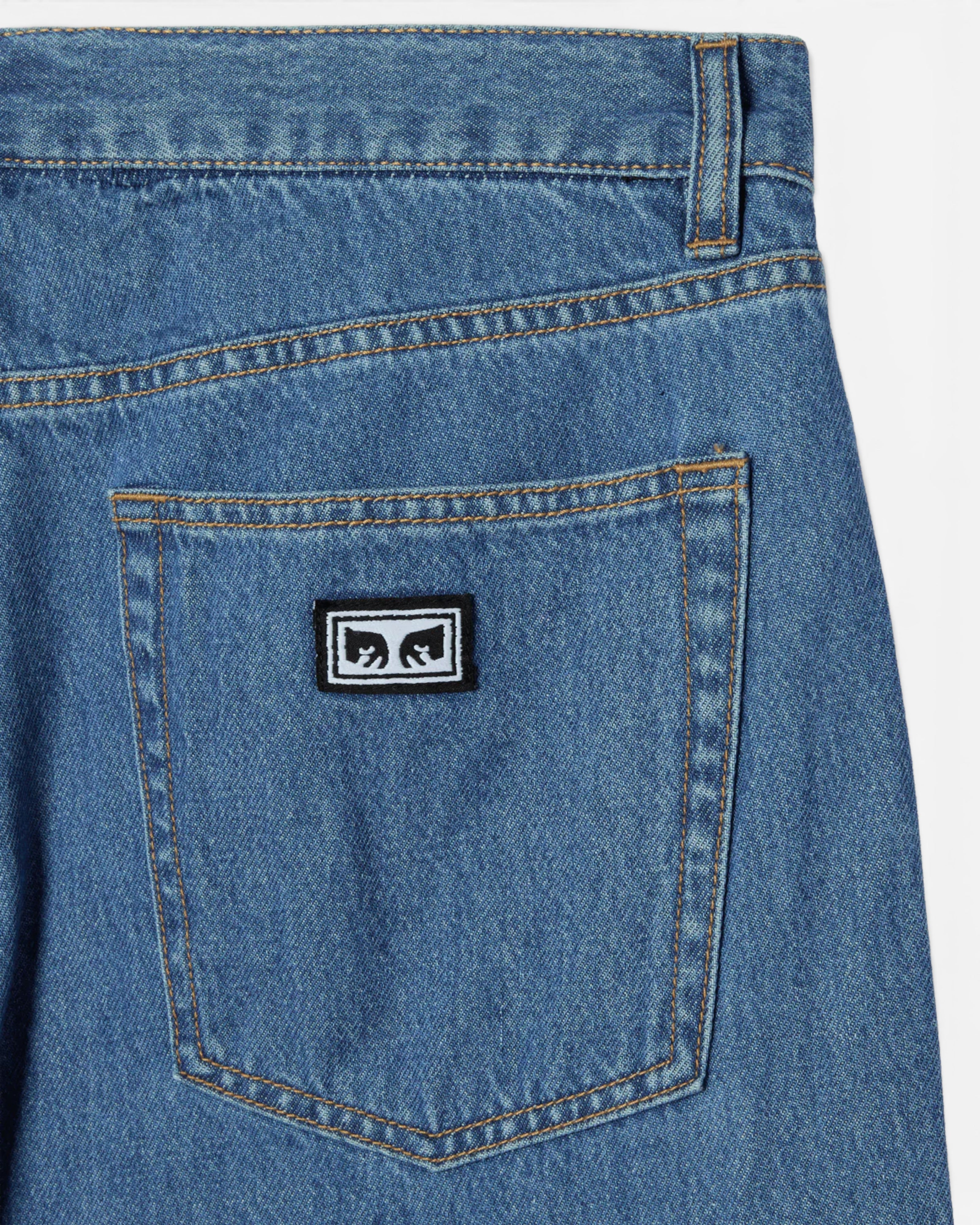 Astrofat Emerson Denim Pant in salty blue stone wash. 100% cotton 10 oz denim with a relaxed fit and tapered leg. Features a classic 5-pocket design and a black and white logo patch on the back pocket.
