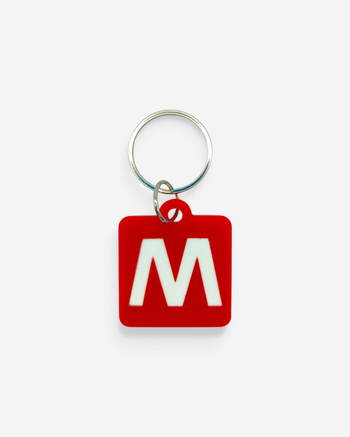 Astrofat Milano subway keychain with a red square rubber tag featuring a white M logo and a silver metal ring