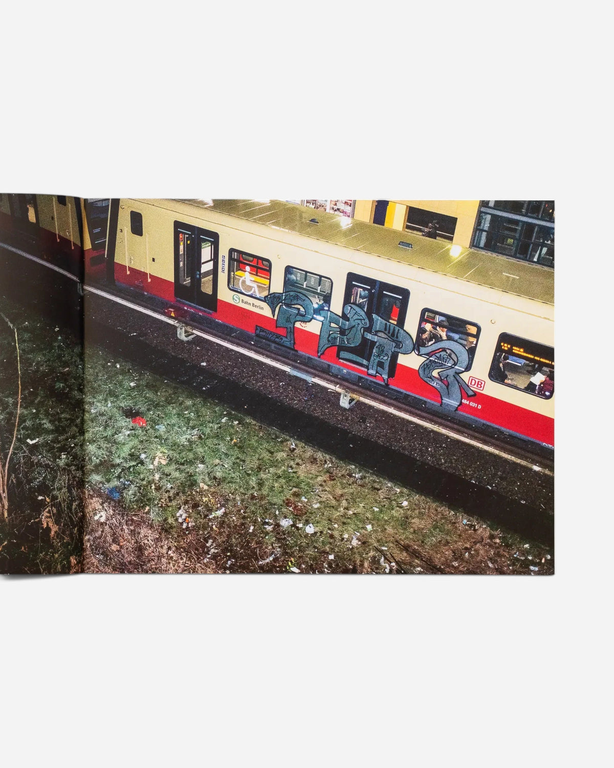 Astrofat photography book open to a page showing a Berlin S-Bahn train with graffiti art moving past a grassy track