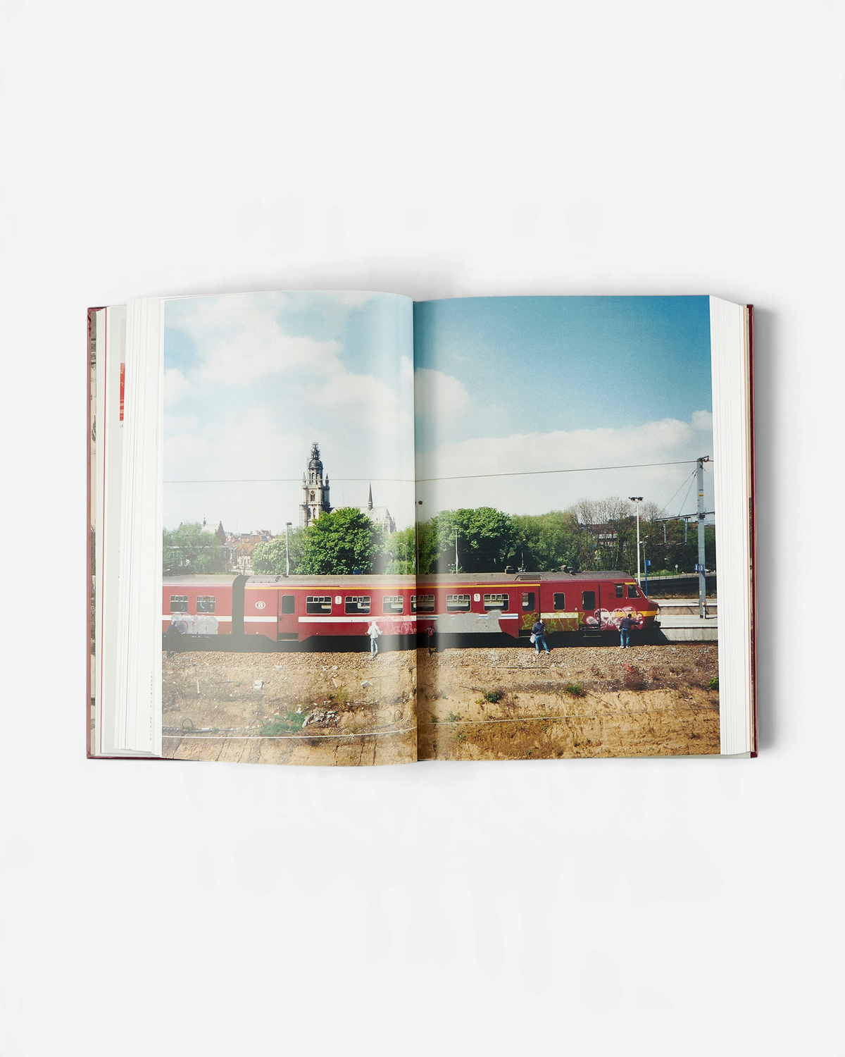 Astrofat Tales From Belgium art book open to a page showing a red train with graffiti in a Belgian landscape.