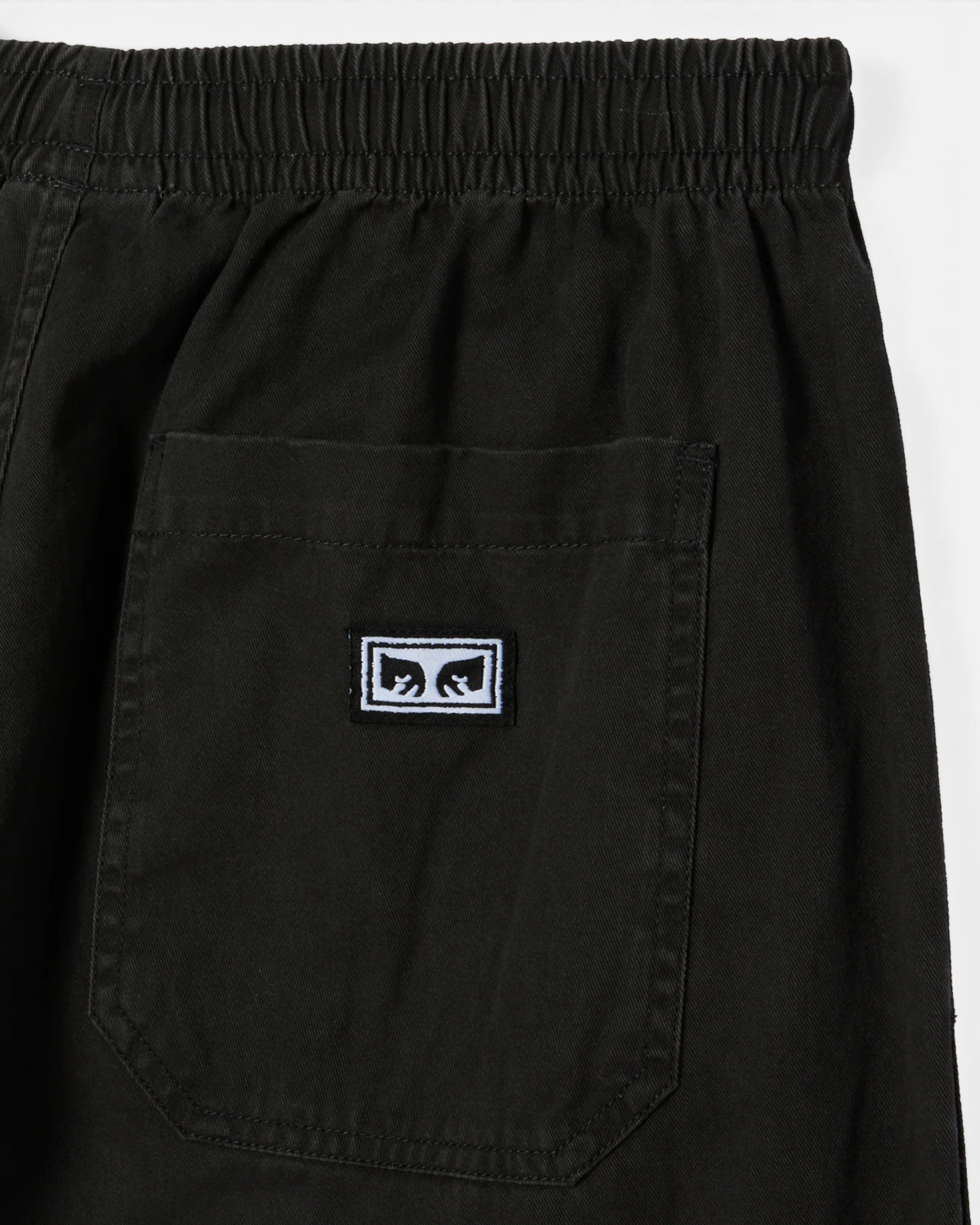 Astrofat Theo Easy Pants in black faded wash cotton. Features elastic waistband, drawstring, front and back pockets, and Obey label.