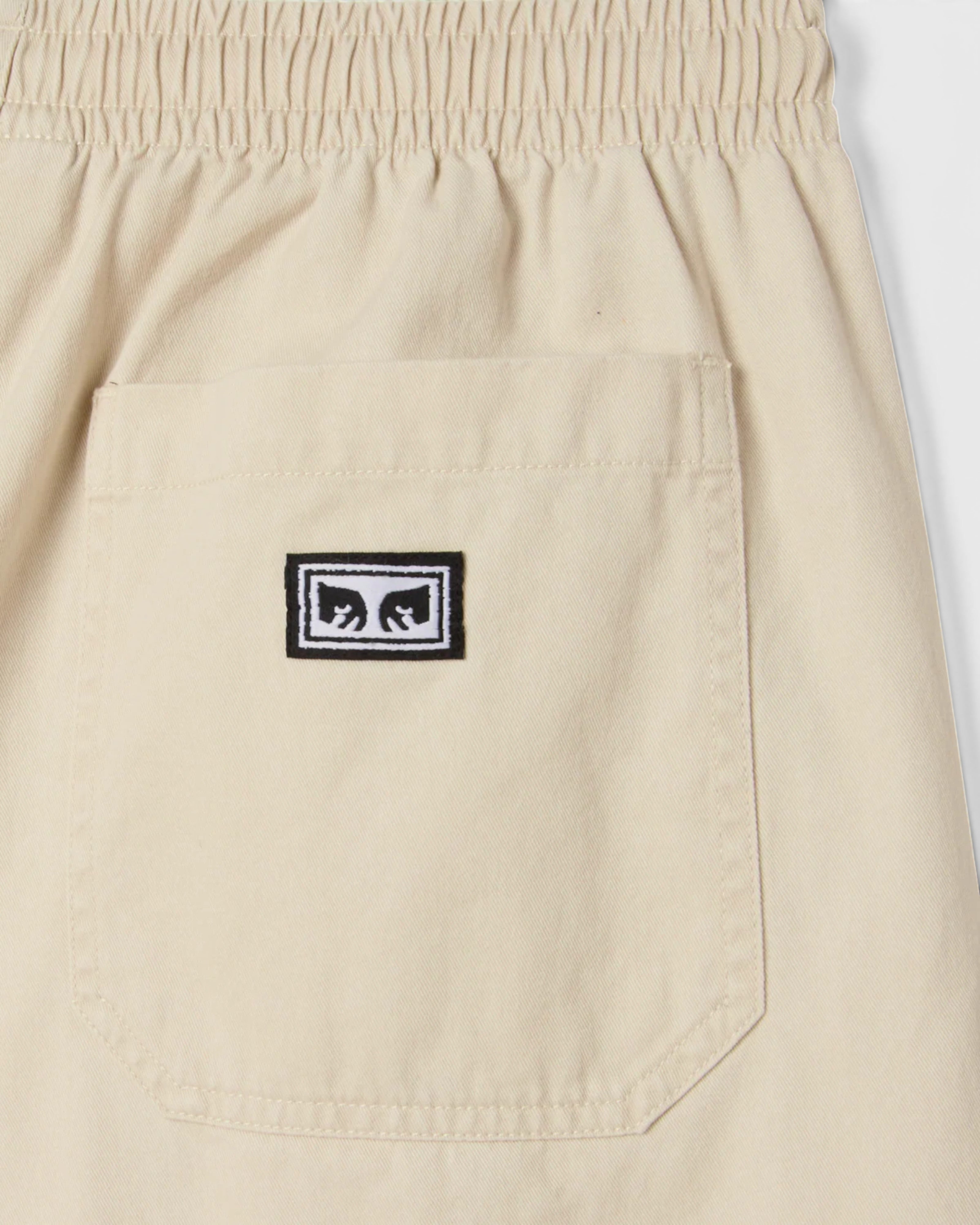 Astrofat Theo Easy Short Brich Faded Wash beige cotton shorts with elastic waistband and drawstring, featuring a faux fly and back patch pockets with an Obey label.