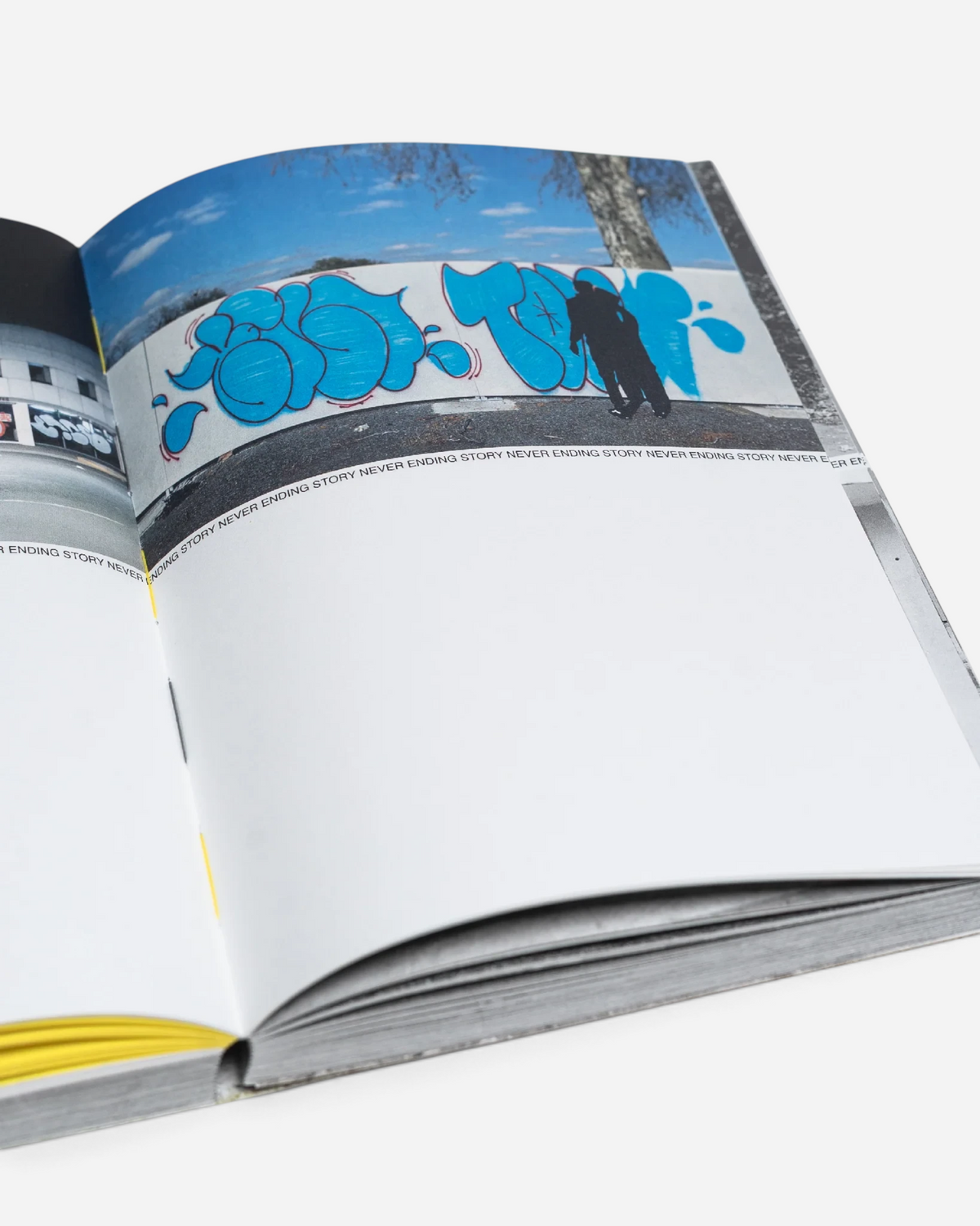 Astrofat Tilt Never Ending Story graffiti book open to a page showing blue throw-up graffiti art on a white wall.