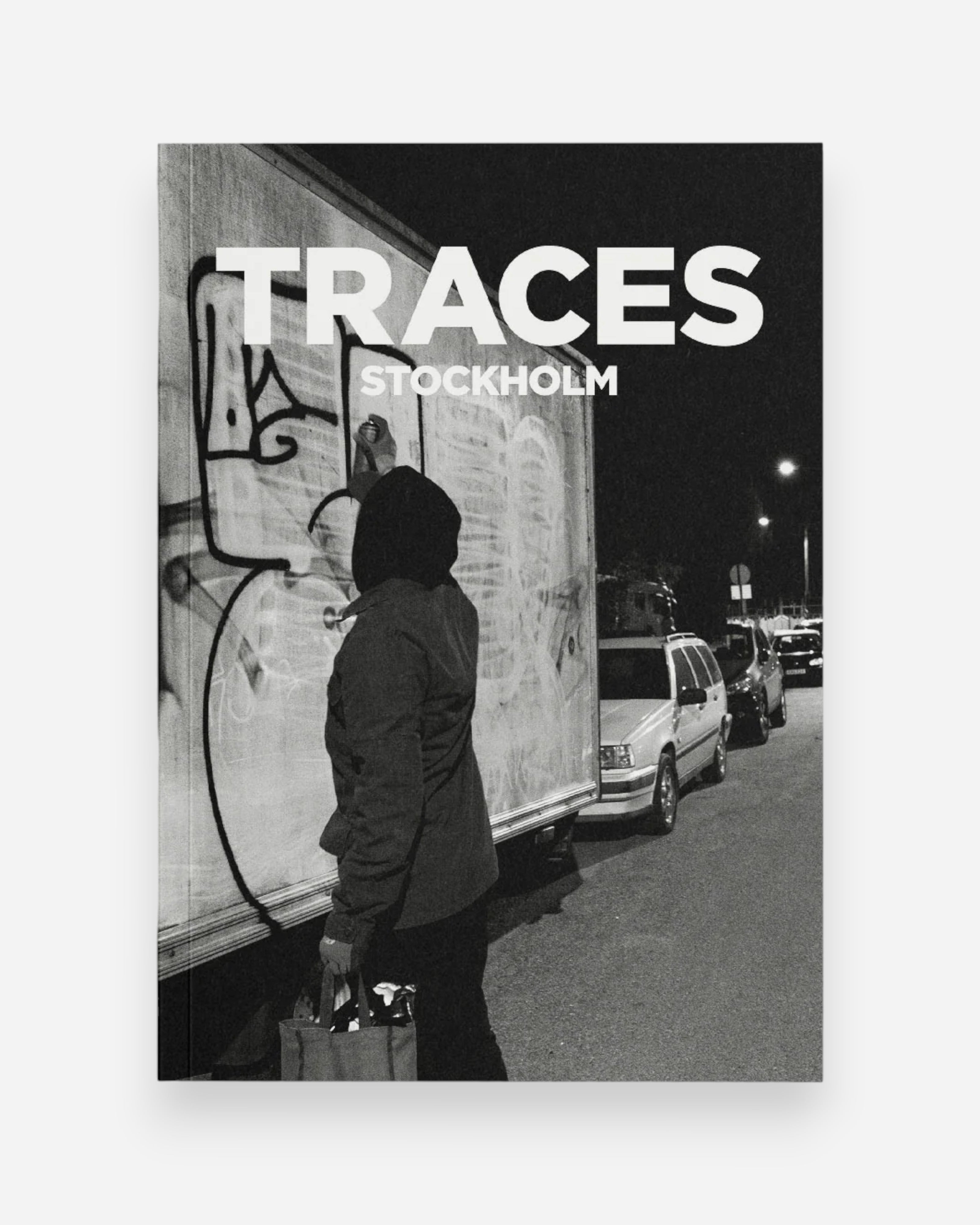 Astrofat Traces Stockholm book cover featuring a person in a hooded jacket spray painting graffiti on a truck at night.